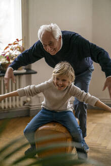 Happy grandfather and grandson playing with buck at home - GUSF02264