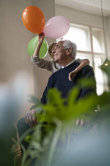 Happy grandfather and grandson playing with balloons at home - GUSF02268