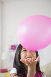 Lächelndes vietnamesisches Mädchen spielt mit rosa Luftballon - BLEF10318