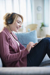 Caucasian woman listening to headphones and digital tablet - BLEF10340