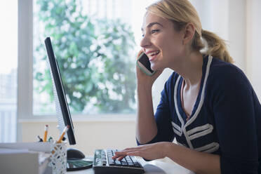 Caucasian businesswoman multi-tasking at desk - BLEF10351