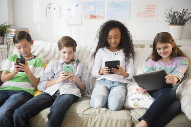 Kinder benutzen Handys und Tablets auf dem Sofa - BLEF10364