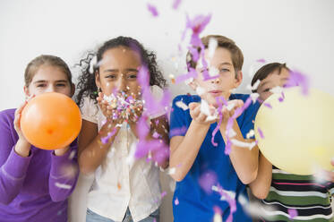 Children blowing party confetti and balloons - BLEF10382