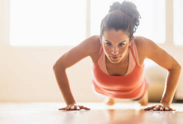 Close up of Hispanic woman doing push-ups in gym - BLEF10388