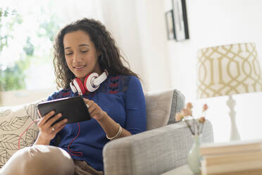Mixed race woman using digital tablet on sofa - BLEF10418