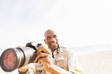 Älterer Mann gemischter Rasse fotografiert am Strand - BLEF10431