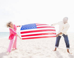 Älteres Paar hält amerikanische Flagge am Strand - BLEF10432