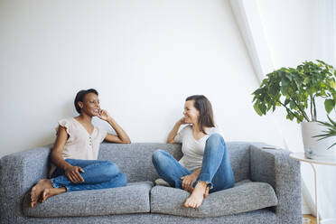 Two relaxed women sitting on couch at home talking - SODF00051