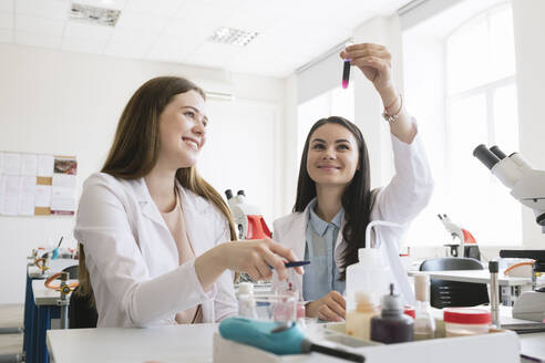 Junge Forscherinnen in weißen Kitteln bei der Analyse einer Laborprobe im naturwissenschaftlichen Unterricht - AHSF00620
