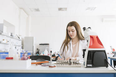 Junger Forscher im weißen Kittel bei der Arbeit in einem Labor - AHSF00623
