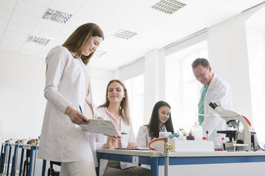 Schüler und Lehrer in weißen Kitteln bei einer Diskussion im naturwissenschaftlichen Unterricht - AHSF00625