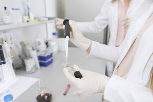 Scientists in white coats preparing sample on microscope slide in lab - AHSF00633