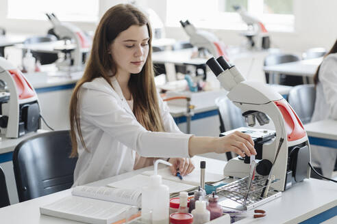 Junge Forscherin im weißen Kittel bei der Arbeit im Labor mit einer Laborprobe - AHSF00667