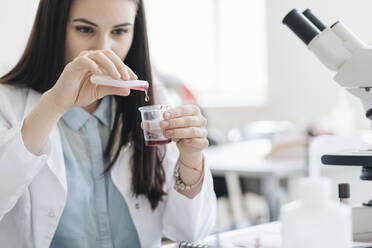 Junge Forscherin im weißen Kittel bei der Arbeit an einer Laborprobe - AHSF00671