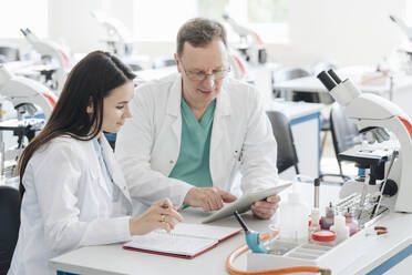 Wissenschaftler in weißen Kitteln verwenden Tablet im Labor - AHSF00679