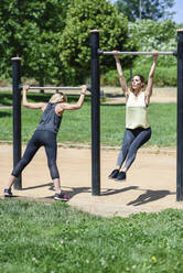 Mature woman exercising with her daughter in a park - JSMF01154