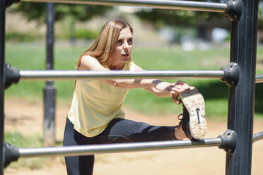 Woman exercising at a bar in a park - JSMF01162