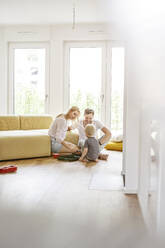 Happy family with a son playing in living room of their new home - PESF01654