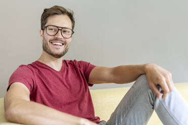 Porträt eines glücklichen Mannes, der auf einer Couch sitzt - PESF01669
