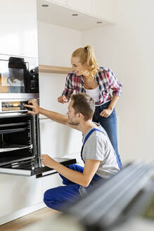 Handwerker beim Einbau eines neuen Backofens in der Küche - PESF01675