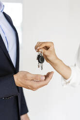 Close-up of real estate agent handing over key to client in new home - PESF01679