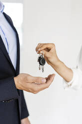 Nahaufnahme eines Immobilienmaklers bei der Übergabe des Schlüssels an den Kunden im neuen Haus - PESF01679