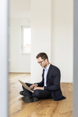 Geschäftsmann sitzt auf dem Boden und benutzt einen Laptop, lizenzfreies Stockfoto