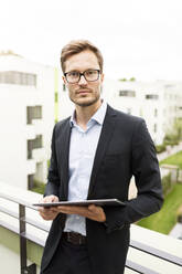 Porträt eines Geschäftsmannes mit Tablet auf einem Balkon in einem Neubaugebiet - PESF01701