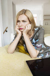 Porträt einer frustrierten jungen Frau mit Tablet auf der Couch zu Hause - PESF01715