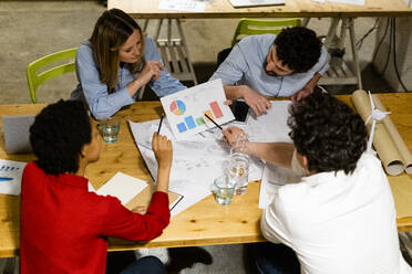 Coworkers having a meeting discussing report in office - GIOF06776