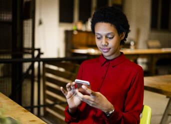 Businesswoman using cell phone at desk in office - GIOF06786