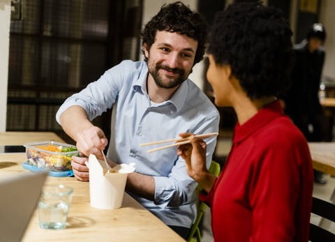 Kollegen im Büro machen Mittagspause und teilen sich chinesisches Essen zum Mitnehmen, lizenzfreies Stockfoto