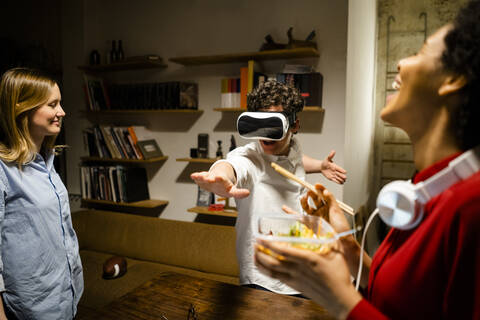 Glückliche Frau mit Kollege mit VR-Brille im Büro, lizenzfreies Stockfoto