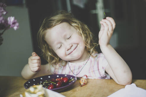 Porträt eines kleinen Mädchens, das Kirschen genießt - IHF00173