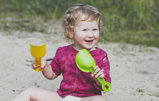 Portrait of happy toddler girl playing with sand - IHF00191