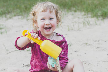 Portrait of happy toddler girl playing with sand - IHF00195
