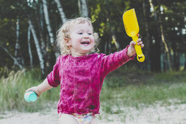 Portrait of happy toddler girl with sandbox toys - IHF00196