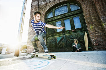 Kaukasischer Mann fährt Skateboard auf dem Bürgersteig - BLEF10501