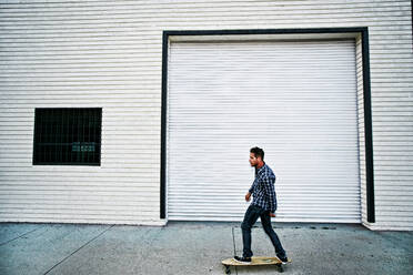 Caucasian man riding skateboard on sidewalk - BLEF10504