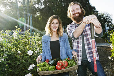 Couple standing with basket of vegetables in garden - BLEF10518