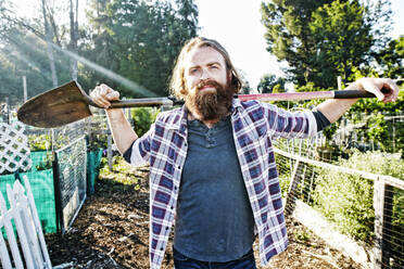 Caucasian man holding shovel in garden - BLEF10519