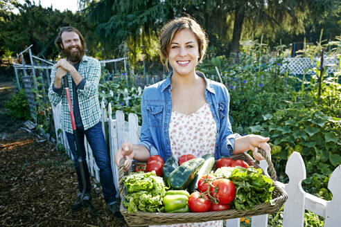 Couple standing with basket of vegetables in garden - BLEF10530