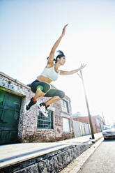 Mixed race woman jumping off sidewalk - BLEF10538