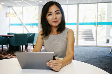 Japanese businesswoman using digital tablet in office - BLEF10562