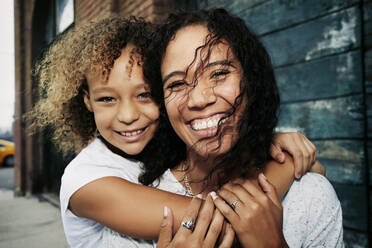 Mixed race mother and daughter hugging outdoors - BLEF10580