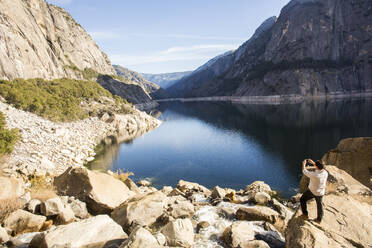 Caucasian man photographing lake in Yosemite National Park, California, United States - BLEF10618