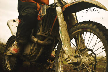 Close up of man riding muddy dirt bike - BLEF10642