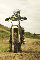 Caucasian man riding dirt bike in field - BLEF10649