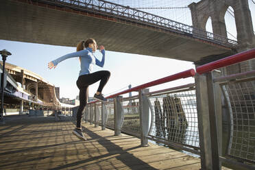 Caucasian runner stretching on waterfront, New York, New York, United States - BLEF10692