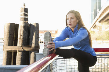 Caucasian runner stretching on waterfront, New York, New York, United States - BLEF10694